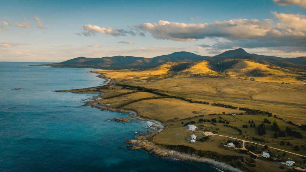 Aerial View Of Tasmanian Waterfront Bordering The Pacific Ocean Under Blue Cloudy Sky