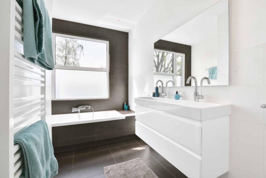 The Bathroom Is In A Minimalist Style With A White Chest Of Drawers